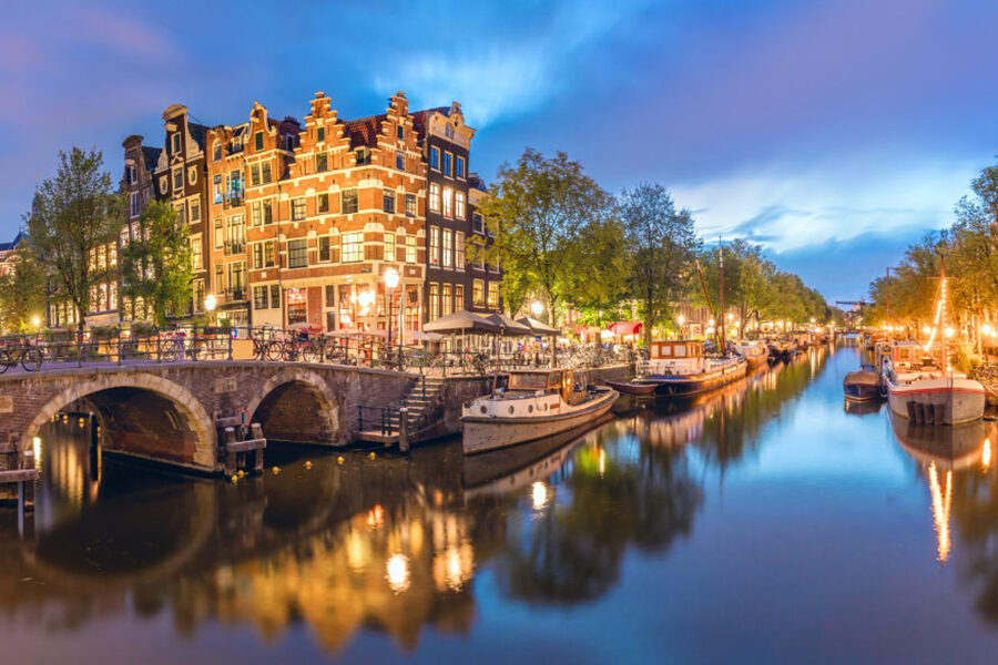 Heimstaden vill sälja fastigheter för 620 miljoner dollar - Panoramic view of the historic city center of Amsterdam. Traditional houses and bridges of Amsterdam town. A romantic evening and a bright reflection of houses in the water.