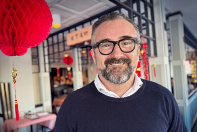 En leende man med skägg och glasögon inne på en Kina-restaurang