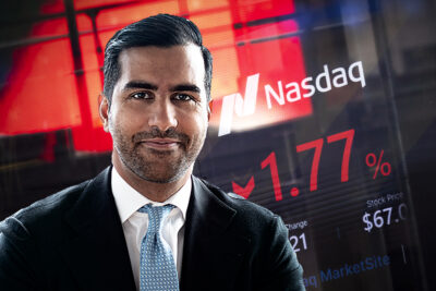 en man i kostym framför en nasdaq display
