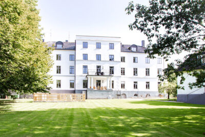 Ringsjöanstalten, en stor gammal byggnad i lummig trädgård